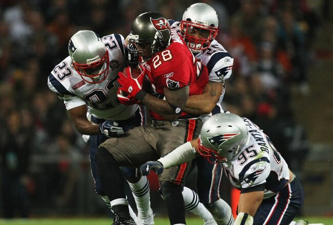 LONDON, ENGLAND - OCTOBER 25:  Derrick Ward (#28) of Tampa Bay Buccaneers is tackled by Leigh Bodden (#23) and Pat Chung (#25) of the New England Patriots during the NFL International Series match between New England Patriots and Tampa Bay Buccaneers at Wembley Stadium on October 25, 2009 in London, England. This is the third occasion where a regular season NFL match has been played in London.  (Photo by Elsa/Getty Images)