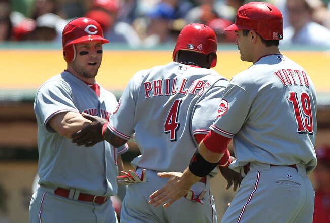 OAKLAND, CA - JUNE 23:  Joey Votto #19 and Brandon Phillips #4 of the Cincinnati Reds celebrate with Laynce Nix #17 after scoring on a single by Jay Bruce against the Oakland Athletics in the first inning during an MLB game at the Oakland-Alameda County Coliseum on June 23, 2010 in Oakland, California. (Photo by Jed Jacobsohn/Getty Images)