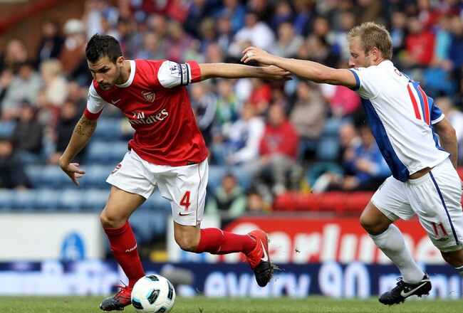 BLACKBURN, ENGLAND - AUGUST 28:   Cesc Fabregas of Arsenal holds off the challenge of Vince Grella of Blackburn Rovers during the Barclays Premier League match between Blackburn Rovers and Arsenal at Ewood Park on August 28, 2010 in Blackburn, England. (Photo by Clive Brunskill/Getty Images)