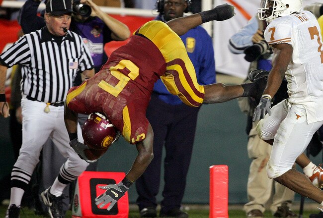 PASADENA, CA - JANUARY 04:  Reggie Bush #5 of the USC Trojans dives over Michael Huff #7 of the Texas Longhorns as he scores a 26 yard touchdown in the fourth quarter of the BCS National Championship Rose Bowl Game at the Rose Bowl on January 4, 2006 in Pasadena, California.   Texas defeated USC 41-38.  (Photo by Harry How/Getty Images)