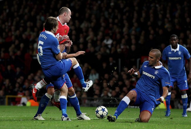 MANCHESTER, ENGLAND - SEPTEMBER 14:  Wayne Rooney of Manchester United is challenged by Madjid Bougherra of Rangers during the UEFA Champions League Group C match between Manchester United and Rangers at Old Trafford on September 14, 2010 in Manchester, England.  (Photo by Alex Livesey/Getty Images)