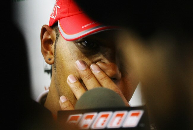 SINGAPORE - SEPTEMBER 26:  Lewis Hamilton of Great Britain and McLaren Mercedes is surrounded as he is interviewed by the media after retiring early following a coming together with Mark Webber of Australia and Red Bull Racing during the Singapore Formula One Grand Prix at the Marina Bay Street Circuit on September 26, 2010 in Singapore.  (Photo by Ker Robertson/Getty Images)