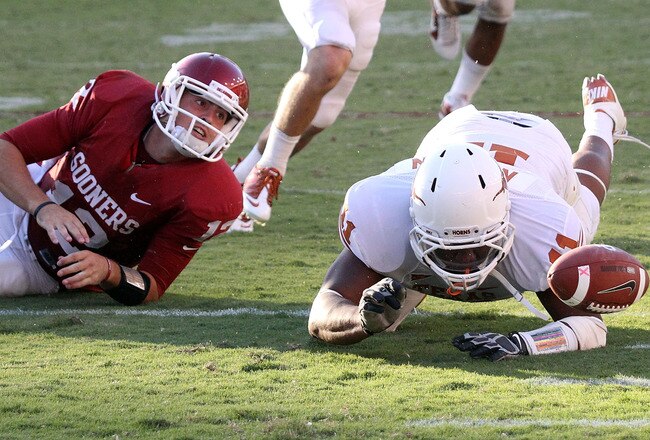 DALLAS - OCTOBER 02:  Quarterback Landry Jones #12 of the Oklahoma Sooners fumbles the ball out of play in front of Jared Norton #11 of the Texas Longhorns in the fourth quarter at the Cotton Bowl on October 2, 2010 in Dallas, Texas.  (Photo by Ronald Martinez/Getty Images)