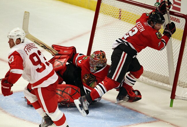 CHICAGO - OCTOBER 09: Duncan Keith #2 of the Chicago Blackhawks falls over teammate Marty Turco #30 and into the net as Johan Franzen #93 of the Detroit Red Wings turns back up the ice during the Blackhawks season home opening game at the United Center on October 9, 2010 in Chicago, Illinois. The Red Wings defeated the Blackhawks 3-2. (Photo by Jonathan Daniel/Getty Images)