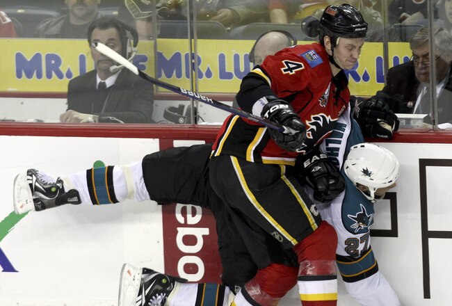 CALGARY, AB -APRIL 6: Jay Bouwmeester #4 of the Calgary Flames pins Manny Malhotra #27 of the San Jose Sharks against the boards in the second period of NHL action on April 6, 2010 at the Pengrowth Saddledome in Calgary, Alberta. (Photo by Mike Ridewood/Getty Images)