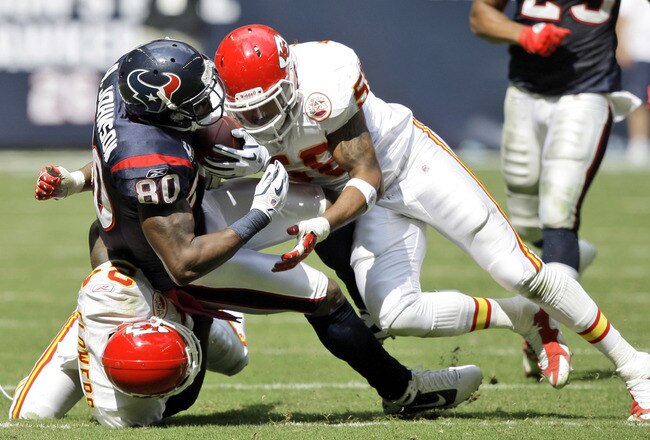 HOUSTON - OCTOBER 17:  Andre Johnson #80 of the Houston Texans is brought down by linebacker Jovan Belcher #59 and cornerback Brandon Flowers #24 at Reliant Stadium on October 17, 2010 in Houston, Texas.  (Photo by Bob Levey/Getty Images)