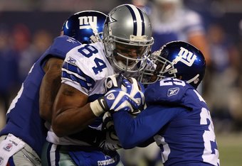 EAST RUTHERFORD, NJ - DECEMBER 06: Aaron Rouse #26 and Bruce Johnson #25 (R) of the New York Giants attempt to strip Patrick Crayton #84 of the Dallas Cowboys after Crayton made a reception in the fourth quarter at Giants Stadium on December 6, 2009 in East Rutherford, New Jersey. (Photo by Jim McIsaac/Getty Images)