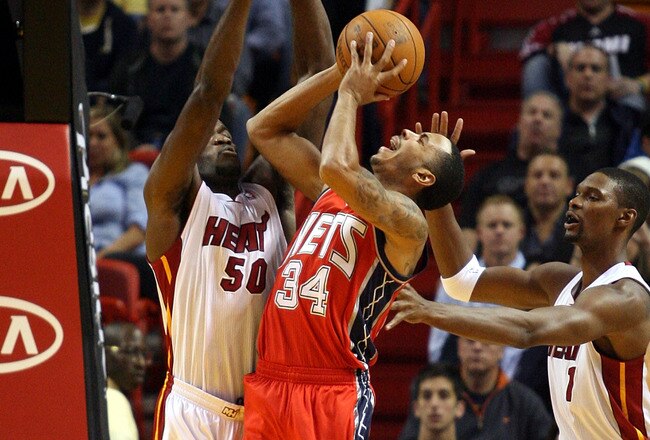 MIAMI - NOVEMBER 06:  Guard Devin Harris #34 of the New Jersey Nets shoots against Joel Anthony #50 and Chris Bosh #1 of the Miami Heat at American Airlines Arena on November 6, 2010 in Miami, Florida. NOTE TO USER: User expressly acknowledges and agrees that, by downloading and or using this photograph, User is consenting to the terms and conditions of the Getty Images License Agreement.  (Photo by Marc Serota/Getty Images)