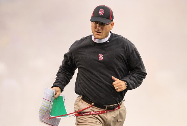 SEATTLE - OCTOBER 30:  Head coach Jim Harbaugh of the Stanford Cardinal runs through a smoke screen as he takes the field prior to the game against the Washington Huskies on October 30, 2010 at Husky Stadium in Seattle, Washington. Stanford won 41-0. (Photo by Otto Greule Jr/Getty Images)