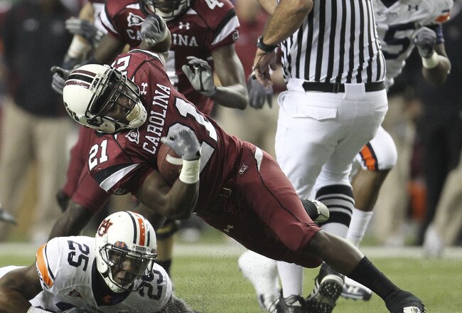 ATLANTA - DECEMBER 4:  Running back Marcus Lattimore #21 of the South Carolina Gamecocks is tackled by Daren Bates #25 of the Auburn Tigers during the 2010 SEC Championship at Georgia Dome on December 4, 2010 in Atlanta, Georgia. (Photo by Mike Zarrilli/Getty Images)