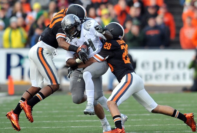 CORVALLIS, OR - DECEMBER 4: Kenjon Barner #24 of the Oregon Ducks struggles for some extra yards as Lance Mitchell #10 and Suaesi Tuimaunei #28 of the Oregon State Beavers in the second quarter of the game at Reser Stadium on December 4, 2010 in Corvallis, Oregon. The Ducks beat the Beavers 37-20 to go on the BCS Championship game on January 10, 2011. (Photo by Steve Dykes/Getty Images)