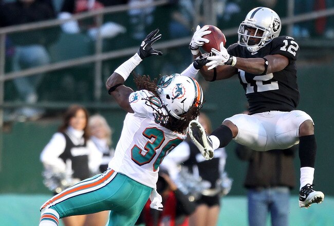 OAKLAND, CA - NOVEMBER 28:  Jacoby Ford #12 of the Oakland Raiders catches the ball while defended by Chris Clemons #30 of the Miami Dolphins at Oakland-Alameda County Coliseum on November 28, 2010 in Oakland, California.  (Photo by Ezra Shaw/Getty Images)