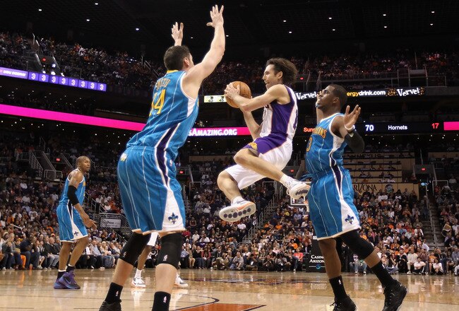 PHOENIX, AZ - JANUARY 30:  Steve Nash #13 of the Phoenix Suns makes a leaping pass guarded by Jason Smith #14 and Chris Paul #3 of the New Orleans Hornets during the NBA game at US Airways Center on January 30, 2011 in Phoenix, Arizona. The Suns defeated the Hornets 104-102. NOTE TO USER: User expressly acknowledges and agrees that, by downloading and or using this photograph, User is consenting to the terms and conditions of the Getty Images License Agreement.  (Photo by Christian Petersen/Getty Images)