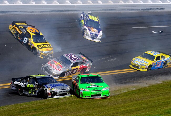 DAYTONA BEACH, FL - FEBRUARY 20:  Marcos Ambrose, driver of the #9 Stanley Ford, David Reutimann, driver of the #00 Aaron's Dream Machine Toyota, Brian Vickers, driver of the #83 Red Bull Toyota, Jimmie Johnson, driver of the #48 Lowe's Chevrolet, and Mark Martin, driver of the #5 GoDaddy.com Chevrolet, are involved in an incident during the NASCAR Sprint Cup Series Daytona 500 at Daytona International Speedway on February 20, 2011 in Daytona Beach, Florida.  (Photo by John Harrelson/Getty Images for NASCAR)