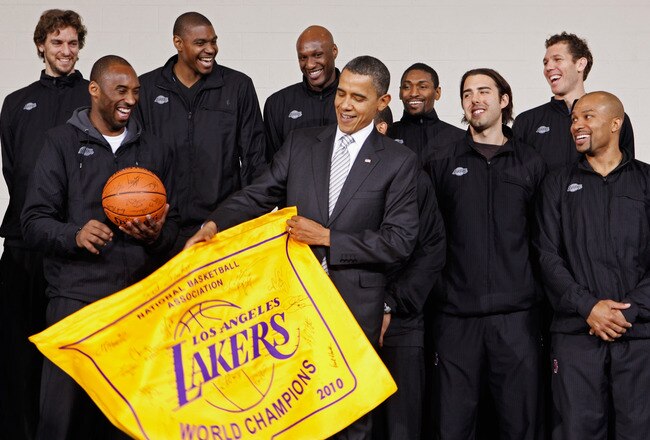 WASHINGTON, DC - DECEMBER 13:  (AFP OUT) U.S. President Barack Obama (C) receives an autographed championship flag and basketball from members of the Los Angeles Lakers (L-R) Paul Gasol, Kobe Bryant, Andrew Bynum, Lamar Odom, Ron Artest, Aleksandar Vujacic, Luke Walton and Derek Fisher during an event at the Boys and Girls Club at THEARC December 13, 2010 in Washington, DC. The 2010 NBA Championship Lakers team volunteered on projects at the club before being honored by the president for their victory.  (Photo by Chip Somodevilla/Getty Images)