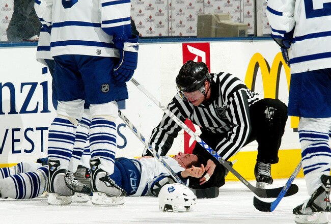 TORONTO - FEBRUARY 10:  Kris Newbury #54 of the Toronto Maple Leafs lays bleeding from the mouth on the ice after a fight against the Pittsburgh Penguins as linesman Scott Driscoll #68 attends to him during the NHL game on February 10, 2007 at the Air Canada Centre in Toronto, Ontario, Canada.  The Penguins won in overtime 6-5.  (Photo By Dave Sandford/Getty Images)
