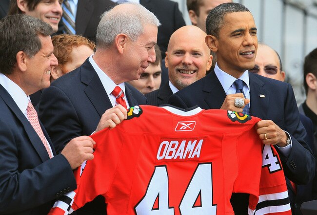 WASHINGTON, DC - MARCH 11:  U.S. President Barack Obama (R) is presented with a hockey jersey and Championship ring by Chicago Blackhawks President John McDonough (C) during an event on the south lawn of the White House on March 11, 2011 in Washington, DC.  Obama hosted the event to honor the Blackhawks for their 2010 Stanley Cup championship victory.  (Photo by Mark Wilson/Getty Images)