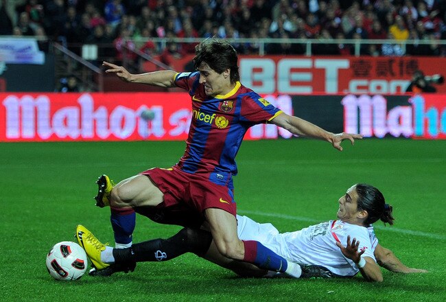 SEVILLE, SPAIN - MARCH 13:  Bojan Krkic (L) of Barcelona scores his sides opening goal past Jose Caceres of Sevilla during the la Liga match between Sevilla and Barcelona at Estadio Ramon Sanchez Pizjuan on March 13, 2011 in Seville, Spain.  (Photo by Jasper Juinen/Getty Images)