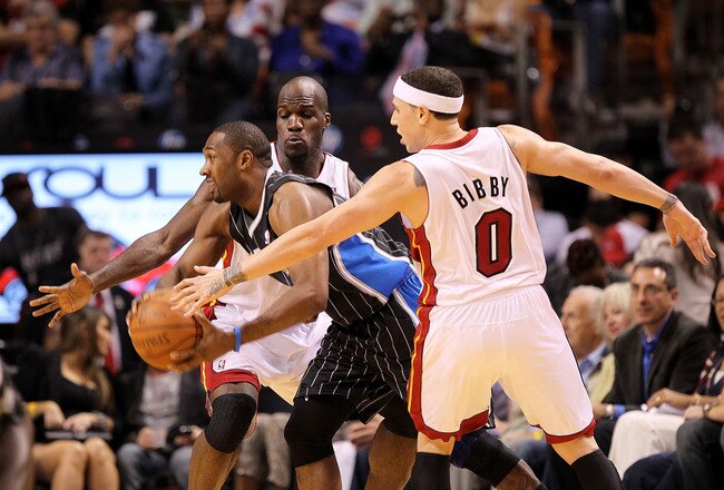 MIAMI, FL - MARCH 03:  Gilbert Arenas #1 of the Orlando Magic passes around Mike Bibby #0 and Joel Anthony #50 of the Miami Heat during a game at American Airlines Arena on March 3, 2011 in Miami, Florida. NOTE TO USER: User expressly acknowledges and agrees that, by downloading and/or using this Photograph, User is consenting to the terms and conditions of the Getty Images License Agreement.  (Photo by Mike Ehrmann/Getty Images)