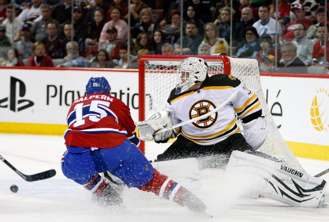 MONTREAL, CANADA - JANUARY 8:  Tim Thomas #30 of the Boston Bruins stretches out to stop the puck in front of Jeff Halpern #15 of the Montreal Canadiens during the NHL game at the Bell Centre on January 8, 2011 in Montreal, Quebec, Canada.  (Photo by Richard Wolowicz/Getty Images)