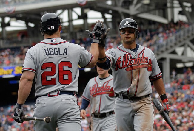 WASHINGTON, DC - APRIL 03: Martin Prado #14 of the Atlanta Braves (R) is congratulated by teammate Dan Uggla #26 after scoring against the Washington Nationals during the seventh inning at Nationals Park on April 3, 2011 in Washington, DC.  (Photo by Rob Carr/Getty Images)