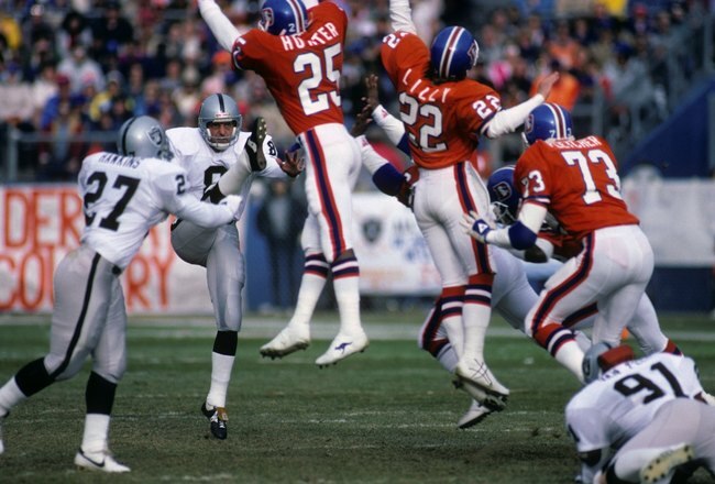 DENVER - DECEMBER 8:  Punter Ray Guy #8 of the Los Angeles Raiders kicks the ball away against defensive backs Daniel Hunter #25, Tony Lilly #22 and linebacker Simon Fletcher #73 of the Denver Broncos during the game at Mile High Stadium on December 8, 1985 in Denver, Colorado.  The Raiders won 17-14 in overtime. (Photo by George Rose/Getty Images)