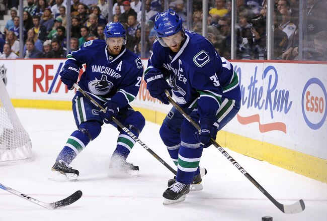 VANCOUVER, CANADA - MAY 24:  Henrik Sedin #33 of the Vancouver Canucks controls the puck as teammate Daniel Sedin #22 looks on in Game Five of the Western Conference Finals against the San Jose Sharks during the 2011 Stanley Cup Playoffs at Rogers Arena on May 24, 2011 in Vancouver, British Columbia, Canada. The Canucks defeated the Sharks 3-2 in the second overtime to win the Western Conference Finals series 4-1. (Photo by Harry How/Getty Images)