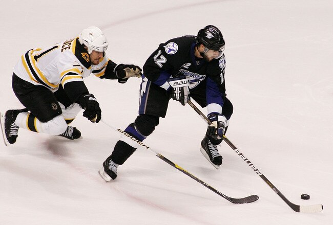 TAMPA, FL - MAY 19:  Andrew Ference #21 of the Boston Bruins skates against Simon Gagne #12 of the Tampa Bay Lightning in Game Three of the Eastern Conference Finals during the 2011 NHL Stanley Cup Playoffs at St Pete Times Forum on May 19, 2011 in Tampa, Florida.  (Photo by Justin K. Aller/Getty Images)