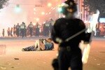 VANCOUVER, BC - JUNE 15:  Riot police walk in the street as a couple kiss on June 15, 2011 in Vancouver, Canada. Vancouver broke out in riots after their hockey team the Vancouver Canucks lost in Game Seven of the Stanley Cup Finals.  (Photo by Rich Lam/Getty Images)