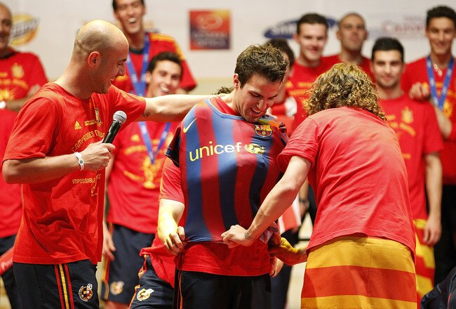 MADRID, SPAIN - JULY 12:  Pepe Reina and Carles Puyol of Spanish national football team put on a shirt of FC Barcelona to Cesc Fabregas during the Spanish team's victory parade following their victory over the Netherlands in the 2010 FIFA World Cup on July 12, 2010 in Madrid, Spain.  (Photo by Angel Martinez/Getty Images)