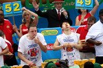 NEW YORK - JULY 4:  Joey Chestnut of San Jose, California (C) and Takeru Kobayashi of Nagano, Japan (R) stuff hot dogs into their mouths during Nathan's Famous Fourth of July hot dog eating contest on July 4, 2009 in Coney Island in the Brooklyn borough of New York City.  Chestnut defeated Kobayashi with eating 68 to his 64.5 hotdogs. Kobayashi won six previous competitions before tying last year with Chestnut. (Photo by Yana Paskova/Getty Images)