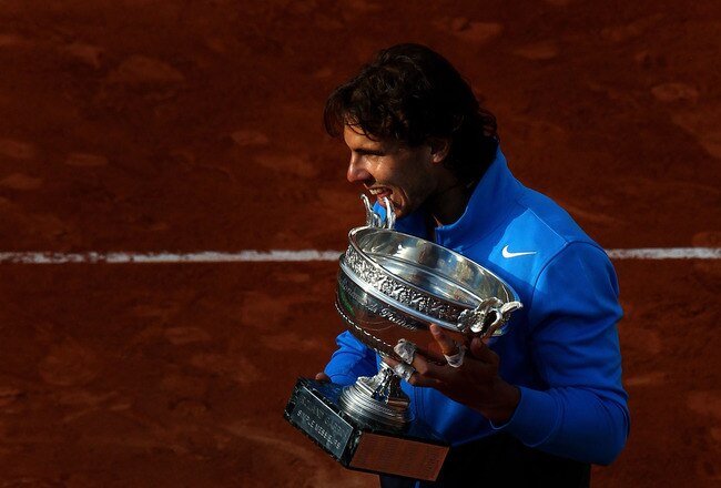 PARIS, FRANCE - JUNE 05:  Champion Rafael Nadal of Spain bites the trophy following his record equalling sixth victory during the men's singles final match between Rafael Nadal of Spain and Roger Federer of Switzerland on day fifteen of the French Open at Roland Garros on June 5, 2011 in Paris, France.  (Photo by Alex Livesey/Getty Images)