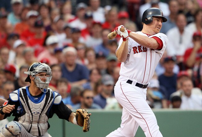 BOSTON, MA - JULY 05:  J.D. Drew #7 of the Boston Red Sox hits an RBI single in the second inning as J.P. Arencibia #9 of the Toronto Blue Jays defends on July 5, 2011 at Fenway Park in Boston, Massachusetts.  (Photo by Elsa/Getty Images)