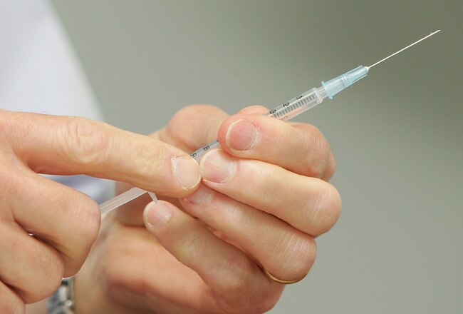 MELBOURNE, AUSTRALIA - NOVEMBER 12:  Dr Peter Braun, Medical Director for the 2010 Australian Olympic Winter Team holds a needle as he prepares to give snowboarder Joh Shaw a vaccination as Shaw takes part in a vaccination program in the lead up to the 2010 Winter Olympic Games at the Victorian Institute of Sport on November 12, 2009 in Melbourne, Australia.  (Photo by Scott Barbour/Getty Images)