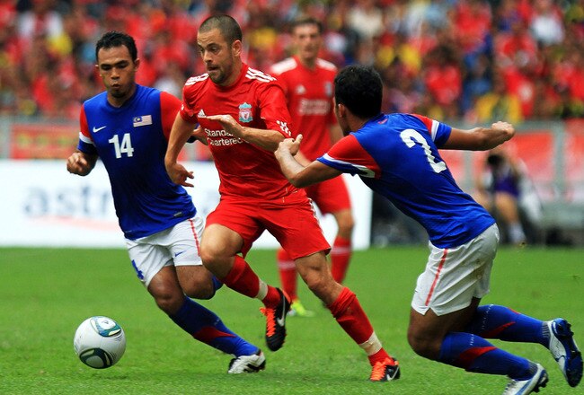KUALA LUMPUR, MALAYSIA - JULY 16: Joe Cole of Liverpool evades tackle from Abdul Hadi Yahaya and Mahalli Jasuli of Malaysia during the pre-season friendly match between Malaysia and Liverpool at the Bukit Jalil National Stadium on July 16, 2011 in Kuala Lumpur, Malaysia. (Photo by Stanley Chou/Getty Images)