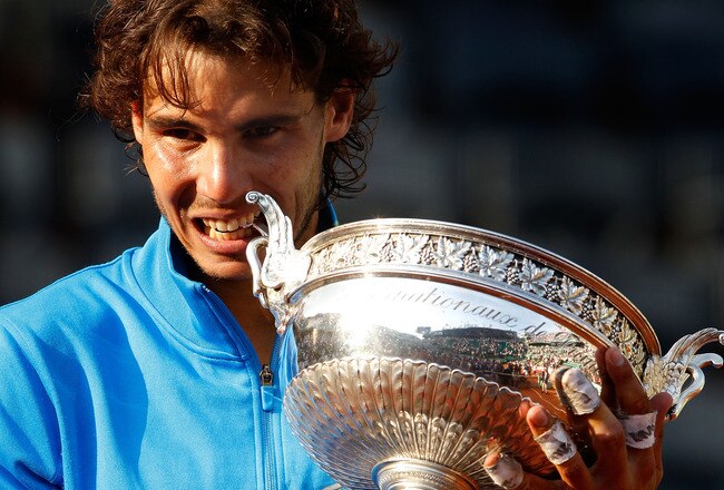 PARIS, FRANCE - JUNE 05:  Champion Rafael Nadal of Spain bites the trophy following his record equalling sixth victory during the men's singles final match between Rafael Nadal of Spain and Roger Federer of Switzerland on day fifteen of the French Open at Roland Garros on June 5, 2011 in Paris, France.  (Photo by Matthew Stockman/Getty Images)