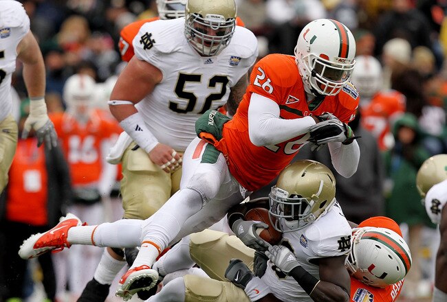 EL PASO, TX - DECEMBER 30:  Running back Cierre Wood #20 of the Notre Dame Fighting Irish is tackled by Ray-Ray Armstrong #26 and Micanor Regis #54 of the Miami Hurricanes at Sun Bowl on December 30, 2010 in El Paso, Texas.  (Photo by Ronald Martinez/Getty Images)