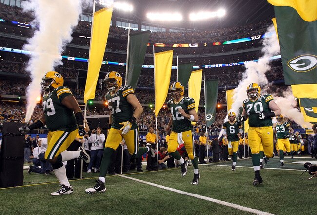 ARLINGTON, TX - FEBRUARY 06:  Ryan Pickett #79, Matt Wilhelm #57, Aaron Rodgers #12 and T.J. Lang #70 of the Green Bay Packers runs out of the tunnel to take on the Pittsburgh Steelers during Super Bowl XLV at Cowboys Stadium on February 6, 2011 in Arlington, Texas.  (Photo by Doug Pensinger/Getty Images)
