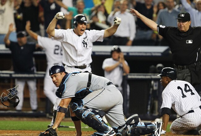 NEW YORK - JULY 16:  Curtis Granderson #14 of The New York Yankees scores the winning run as he beats the tag of Kelly Shoppach #10 of TheTampa Bay Rays as Mark Teixeira #25 celebrates  from a Nick Swisher hit in the ninth inning on July 16, 2010 at Yankee Stadium in the Bronx Borough of New York City.  (Photo by Al Bello/Getty Images)