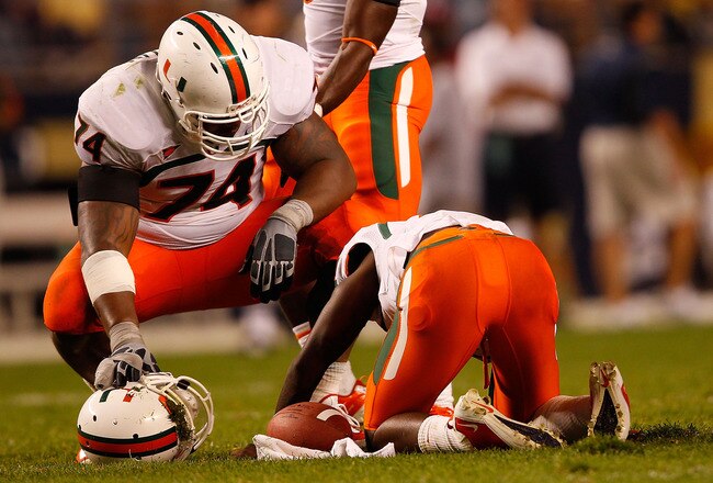 PITTSBURGH - SEPTEMBER 23:  Jacory Harris #12 of the Miami Hurricanes lays on the ground as teammate Orlando Franklin #74 looks on after being sacked by the Pittsburgh Panthers on September 23, 2010 at Heinz Field in Pittsburgh, Pennsylvania.  (Photo by Jared Wickerham/Getty Images)
