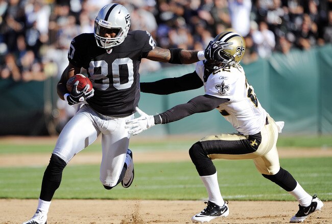 OAKLAND, CA - AUGUST 28:  Derek Hagan #80 of the Oakland Raiders stiff arms Tracy Porter #22 of the New Orleans Saints and runs thirty five yards for a touchdown in the first quarter during an NFL pre-season football game at the O.co Coliseum August 28, 2011 in Oakland, California. (Photo by Thearon W. Henderson/Getty Images)