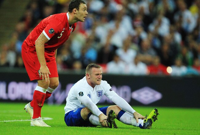 LONDON, ENGLAND - SEPTEMBER 06:  Wayne Rooney (R) of England reacts after being tackled by Darcy Blake (L) of Wales during the UEFA EURO 2012 group G qualifying match between England and Wales at Wembley Stadium  on September 6, 2011 in London, England.  (Photo by David Cannon/Getty Images)