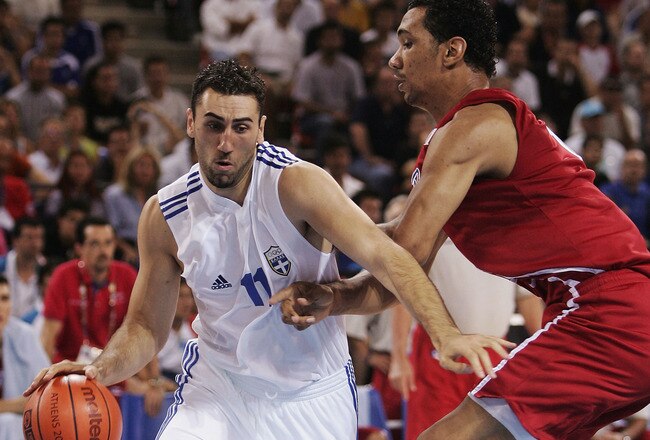 ATHENS - AUGUST 23:  Dimosthenis Ntikoudis of Greece attacks the ball in front of Peter John Ramos of Puerto Rico in the men's basketball preliminary game between Greece and Puerto Rico on August 23, 2004 during the Athens 2004 Summer Olympic Games at the Indoor Arena of the Helliniko Olympic Complex in Athens, Greece. (Photo by Stuart Hannagan/Getty Images)