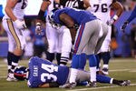 EAST RUTHERFORD, NJ - SEPTEMBER 19:  Deon Grant #34 of the New York Giants lies on the turf as teammate Kenny Phillips #21 stands over him against the St. Louis Rams at MetLife Stadium on September 19, 2011 in East Rutherford, New Jersey.  (Photo by Nick Laham/Getty Images)