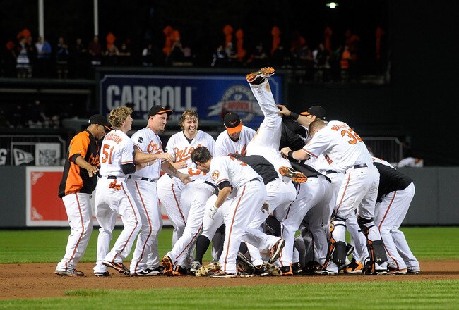 BALTIMORE, MD - SEPTEMBER 28:  Robert Andino #11 of the Baltimore Orioles is mobbed by teammates after driving in the game winning run in the ninth inning against the Boston Red Sox at Oriole Park at Camden Yards on September 28, 2011 in Baltimore, Maryland. Baltimore won the game 4-3.  (Photo by Greg Fiume/Getty Images)