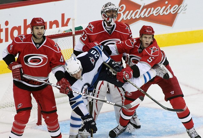 WINNIPEG, CANADA - SEPTEMBER 28: Troy Bodie #20 of the Winnipeg Jets is given pressure by Bryan Allen #5 of the Carolina Hurricanes in front of goalie Brian Boucher #33 and Jay Harrison #44 in preseason NHL action at the MTS Centre on September 28, 2011 in Winnipeg, Manitoba, Canada. (Photo by Marianne Helm/Getty Images)