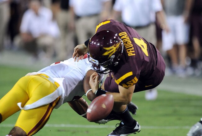 TEMPE, AZ - SEPTEMBER 24:  Aaron Pflugrad #4 of the Arizona State Sun Devils fumbles the ball after getting hit against the University of Southern California Trojans at Sun Devil Stadium on September 24, 2011 in Tempe, Arizona.  (Photo by Norm Hall/Getty Images)