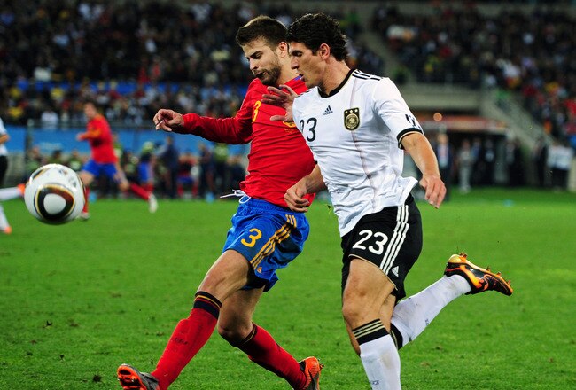 DURBAN, SOUTH AFRICA - JULY 07:  Gerard Pique of Spain challenges Mario Gomez of Germany during the 2010 FIFA World Cup South Africa Semi Final match between Germany and Spain at Durban Stadium on July 7, 2010 in Durban, South Africa.  (Photo by Clive Mason/Getty Images)