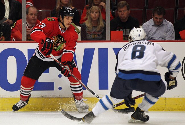 CHICAGO, IL - OCTOBER 13: Daniel Carcillo #13 of the Chicago Blackhawks controls the puck as Alexander Burmistrov #8 of the Winnipeg Jets closes in at the United Center on October 13, 2011 in Chicago, Illinois.  (Photo by Jonathan Daniel/Getty Images)