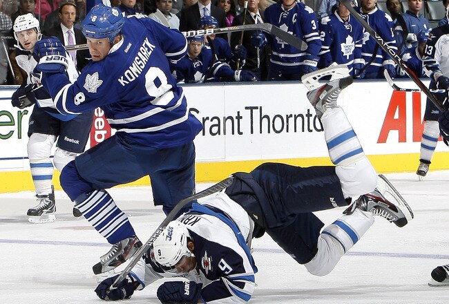 TORONTO, CANADA - OCTOBER 19: Mike Komisarek #8 of the Toronto Maple Leafs trips Evander Kane #9 of the Winnipeg Jets during NHL action at the Air Canada Centre October 19, 2011 in Toronto, Ontario, Canada. (Photo by Abelimages/Getty Images)